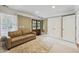 Inviting bedroom featuring neutral color palette, large window, double doors, and modern leather couch at 55 Fleming Forest Dr, Youngsville, NC 27596