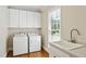 Well-lit laundry room with modern washer, dryer, sink, and storage cabinets above for efficient organization at 55 Fleming Forest Dr, Youngsville, NC 27596