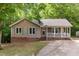 Charming home with light brown siding, blue shutters, brick foundation and covered porch with white railings at 5600 Sherrif W Pl, Raleigh, NC 27610