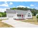 Front exterior with white siding, gray roof, driveway, and manicured flowerbeds at 5612 Sandy Trail Dr, Knightdale, NC 27545