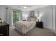 Well-lit bedroom with a large bed, balcony access, and light-colored walls and neutral carpet at 568 Piney Mountain Rd, Chapel Hill, NC 27514