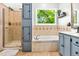 Bathroom features a tiled shower, soaking tub under a window, and painted cabinets at 5701 Hadrian Dr Dr, Durham, NC 27703