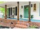 Close-up of a charming front porch with a seating area and stylish green door at 5701 Hadrian Dr Dr, Durham, NC 27703