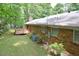 Cozy backyard showcasing the brick house and wooden deck, surrounded by lush greenery and a serene atmosphere at 5825 Scalybark Rd, Durham, NC 27712