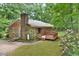 Brick home with a deck, surrounded by mature trees and flowering bushes enhancing its curb appeal at 5825 Scalybark Rd, Durham, NC 27712