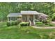 Charming brick home with well-manicured lawn, shrubbery, and a rhododendron bush at 5825 Scalybark Rd, Durham, NC 27712