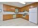 Traditional-style kitchen featuring wooden cabinets, white appliances, and a window overlooking the greenery at 5825 Scalybark Rd, Durham, NC 27712