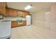 Kitchen with wooden cabinets, white appliances, patterned walls, and light tile flooring at 5825 Scalybark Rd, Durham, NC 27712