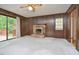 Spacious living room with wood-paneled walls, brick fireplace, and access to the outdoor deck at 5825 Scalybark Rd, Durham, NC 27712