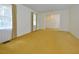 Large living room with vintage carpet, offering ample space and plenty of natural light from the windows at 5825 Scalybark Rd, Durham, NC 27712