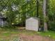 Exterior of a small storage shed nestled among mature trees in a private backyard setting at 6125 Bellow St, Raleigh, NC 27609