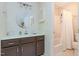 Bathroom featuring a dark vanity, round mirror and tiled tub/shower at 6922 Saxby Ct, Raleigh, NC 27613