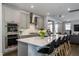 Kitchen with island, gray cabinets, double ovens, and stainless steel range hood at 745 Orange Oak Ln, Apex, NC 27523