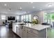 Open concept kitchen with a large island, stainless steel sink, and a view of the living room and outdoor patio at 745 Orange Oak Ln, Apex, NC 27523