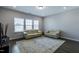A cozy living area featuring hardwood floors, two large sofas, and ample natural light from large windows at 745 Orange Oak Ln, Apex, NC 27523