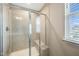 Tiled walk-in shower with a glass door, built-in seat, and a window for natural light at 805 Grafton Peak Lane Ln, Apex, NC 27523