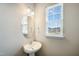 Stylish powder room featuring a pedestal sink, round mirror and bright natural light at 805 Grafton Peak Lane Ln, Apex, NC 27523