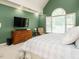 Well-lit bedroom with a window, wooden dresser, mounted television, and a relaxing chair at 816 Roanoke Dr, Cary, NC 27513