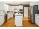 Open kitchen with stainless steel refrigerator, island, and white cabinetry at 816 Roanoke Dr, Cary, NC 27513