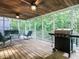 Screened porch with wood flooring, seating, and a grill, overlooking a wooded area at 816 Roanoke Dr, Cary, NC 27513