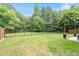 Large, grassy backyard with black iron fence and large trees. Includes patio and furniture at 8408 Haines Creek Ln, Raleigh, NC 27616