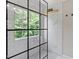 Modern bathroom featuring black framed shower, marble tile, pebble floor and window overlooking trees at 8408 Haines Creek Ln, Raleigh, NC 27616