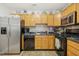 Well-lit kitchen features stainless steel refrigerator, wood cabinetry, and black appliances at 8640 Neuse Landing Ln # 110, Raleigh, NC 27616