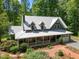Aerial view of a two-story home with metal roof, wraparound porch and landscaped yard surrounded by lush trees at 9625 Collins Creek Dr, Chapel Hill, NC 27516