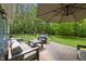 Back deck with outdoor seating under an umbrella and view of the wooded backyard at 9625 Collins Creek Dr, Chapel Hill, NC 27516