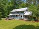 Expansive backyard of a blue two-story home with a metal roof, deck, and screened in porch at 9625 Collins Creek Dr, Chapel Hill, NC 27516