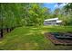 Spacious backyard featuring a large grassy area, garden beds, and wooded perimeter at 9625 Collins Creek Dr, Chapel Hill, NC 27516