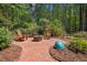 Relaxing backyard with a brick patio, fire pit, Adirondack chairs, and mature trees at 9625 Collins Creek Dr, Chapel Hill, NC 27516