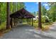 Carport with exposed rafters and gravel driveway, enveloped by mature trees at 9625 Collins Creek Dr, Chapel Hill, NC 27516