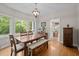 Dining area with wood table and bench seating, large windows, and chandelier lighting at 9625 Collins Creek Dr, Chapel Hill, NC 27516