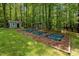 Garden area with raised beds and sheds amidst a serene, wooded landscape at 9625 Collins Creek Dr, Chapel Hill, NC 27516