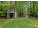 Two outbuildings with shed doors nestled among tall trees and greenery at 9625 Collins Creek Dr, Chapel Hill, NC 27516