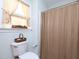 Cozy bathroom featuring a decorative shower curtain, window with tied-back curtains, and toilet with basket on top at 101 Cardinal Dr, Youngsville, NC 27596