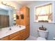 Well-lit bathroom featuring a wood vanity, large mirror, and a classic white toilet at 101 Cardinal Dr, Youngsville, NC 27596