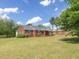 A well-maintained red brick house features a classic design and is surrounded by a green lawn and landscaping at 10186 W Nc-97 Hwy, Middlesex, NC 27557