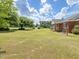 Expansive front yard with mature trees and view of the red brick home with white trim at 10186 W Nc-97 Hwy, Middlesex, NC 27557