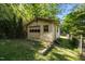 Backyard shed in a wooded area with garage doors and a side door, offering ample storage at 108 Jefferson Dr, Durham, NC 27712