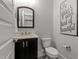 Well-lit powder room featuring modern fixtures, dark vanity, toilet and decorative black and white tile floor at 15 Willow Bend Dr, Youngsville, NC 27596