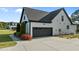 Side view of a two-car garage, set back from the house, with an asphalt driveway and manicured landscaping at 15 Willow Bend Dr, Youngsville, NC 27596