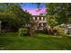 Charming two-story home with red shutters, lovely landscaping, and a lush lawn surrounded by mature trees at 1924 Strebor St, Durham, NC 27705