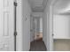 A hallway with white walls leading to rooms with carpeted floors, closed white doors, and neutral decor at 1924 Strebor St, Durham, NC 27705
