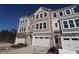 New townhome with attached garage and a mixed material facade of siding and stone under a clear blue sky at 2297 Bay Minette Sta # 536, Apex, NC 27502