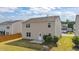 Tan two-story home featuring a grassy backyard with small patio area and a white door at 2522 Dalmahoy Ln, Fuquay Varina, NC 27526