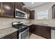 Close-up of the kitchen with stainless steel range, microwave, granite counters, and tiled backsplash at 2522 Dalmahoy Ln, Fuquay Varina, NC 27526