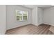 Bright, empty room with wood-look flooring, one window with blinds, and white walls at 2522 Dalmahoy Ln, Fuquay Varina, NC 27526