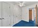 Bright bedroom featuring blue carpet, three closets, and ceiling fan lighting at 2608 Foxgate Dr, Raleigh, NC 27610